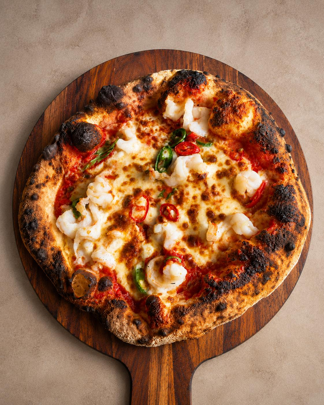 Woodfired prawn and chilli signature pizza on a wooden board — Bello Signatures